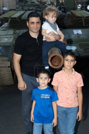 Téléchargez les photos : KYIV, UKRAINE - 24 août 2023 : Un jeune père et ses enfants sont photographiés près d'un réservoir incendié - en image libre de droit