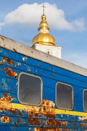 Foto de Un carruaje ferroviario ucraniano disparado por tropas rusas se ve frente a la Iglesia Mykhailivska en la Plaza Mykhailivska en Kiev. - Imagen libre de derechos