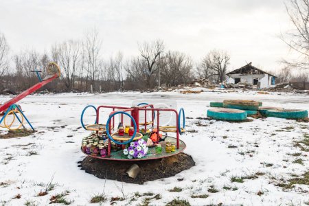 Gedenkkerzen zum Gedenken an die Opfer auf einem Kinderkarussell auf einem Spielplatz in der Nähe des Raketenangriffsortes am 5. Oktober 2023 im Dorf Groza, Bezirk Kupyanskiy, Gebiet Charkiw, Ukraine
