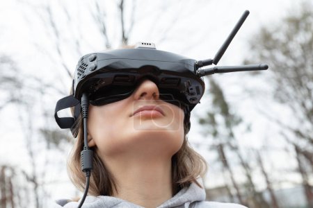 Téléchargez les photos : LVIV, UKRAINE - 11 février 2024 : Une jeune femme porte des lunettes de réalité virtuelle alors qu'elle apprend à piloter un drone FPV - en image libre de droit