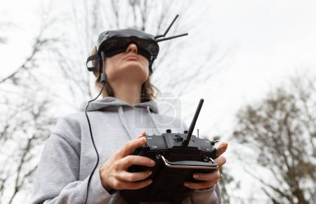 Téléchargez les photos : LVIV, UKRAINE - 11 février 2024 : Une jeune femme porte des lunettes de réalité virtuelle et une télécommande alors qu'elle apprend à piloter un drone FPV - en image libre de droit