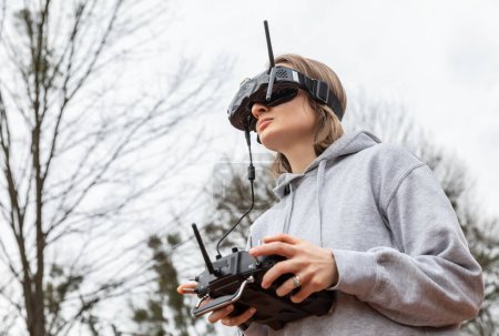 Téléchargez les photos : LVIV, UKRAINE - 11 février 2024 : Une jeune femme porte des lunettes de réalité virtuelle et une télécommande alors qu'elle apprend à piloter un drone FPV - en image libre de droit