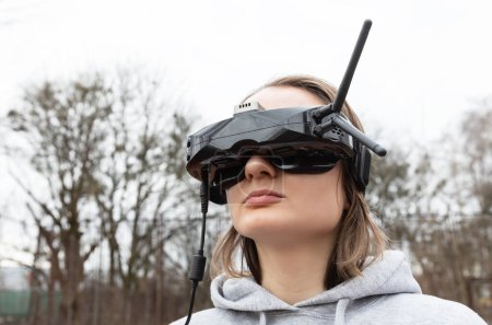 Téléchargez les photos : LVIV, UKRAINE - 11 février 2024 : Une jeune femme porte des lunettes de réalité virtuelle alors qu'elle apprend à piloter un drone FPV - en image libre de droit