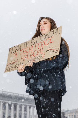 Photo for KYIV, UKRAINE - Feb. 18, 2024: A young woman with a placard "While you are in captivity I am your voice on the outside" is seen during the action in support of prisoners of war FREE AZOV. - Royalty Free Image