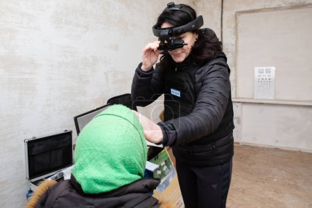 Téléchargez les photos : CHASIV YAR, DONETSK REG., UKRAINE - mars 2024 : Une ophtalmologiste de la mission FRIDA Ukraine examine une femme âgée à l'aide d'un équipement médical mobile de pointe - en image libre de droit