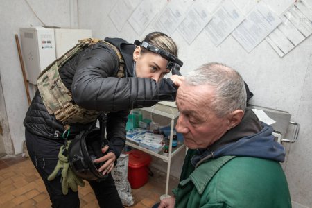 Téléchargez les photos : SIVERSK, DONETSK REG., UKRAINE - mars 2024 : Un médecin de la mission de volontaires Frida Ukraine effectue des procédures médicales sur des résidents locaux âgés en quête d'assistance médicale - en image libre de droit