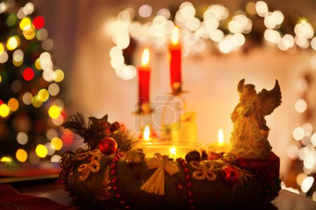 Foto de Interior de Navidad con velas, corona y ángel en la mesa. Fondo de la sala de vacaciones de invierno con luces y chimenea. Misterio Nochebuena Nochebuena - Imagen libre de derechos