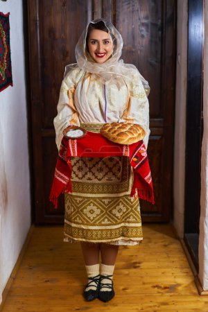 Foto de Mujer rumana joven en traje popular novia tradicional que ofrece pan y sal como bienvenida - Imagen libre de derechos