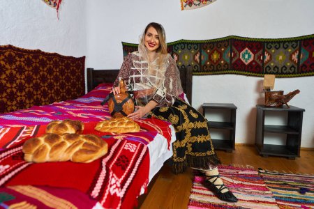 Foto de Mujer rumana joven vestida con traje popular tradicional, en una casa rural tradicional - Imagen libre de derechos
