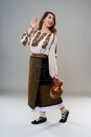 Téléchargez les photos : Jeune femme en costume roumain traditionnel vintage populaire, isolé sur fond gris - en image libre de droit