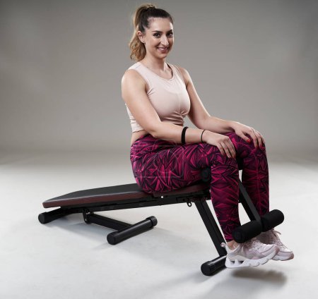 Téléchargez les photos : Confiant forte femme taille plus faire abdos croque sur un banc de fitness - en image libre de droit