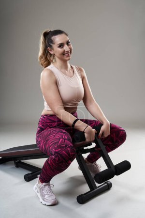 Photo for Confident strong plus size woman doing abs crunches on a fitness bench - Royalty Free Image