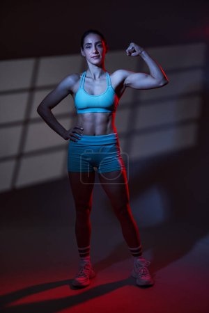 Téléchargez les photos : Attrayant brunette latino modèle de fitness féminin sur fond gris avec ombre de fenêtre comme arrière-plan - en image libre de droit