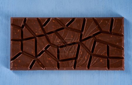 Téléchargez les photos : Milk chocolate with hazelnuts and peanuts crushed inside on a blue wooden board - en image libre de droit