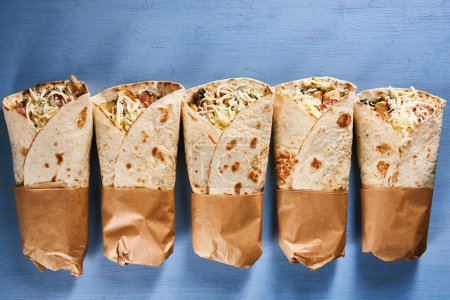 Téléchargez les photos : Burrito roll wraps on a blue wooden board - en image libre de droit