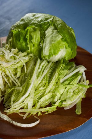 Foto de Chopped and halved fresh white cabbage on a wooden cutting board on blue background - Imagen libre de derechos