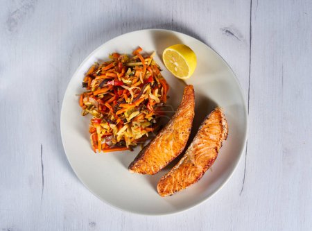 Photo for Salmon steaks and stir fry vegetables with lemon on a plate - Royalty Free Image