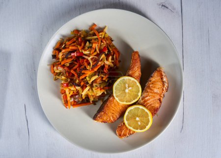 Photo for Salmon steaks and stir fry vegetables with lemon on a plate - Royalty Free Image