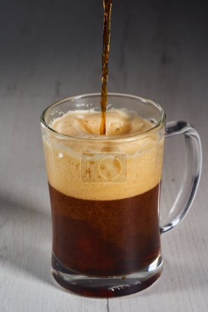 Foto de Pouring brown beer in a glass half a litre mug - Imagen libre de derechos