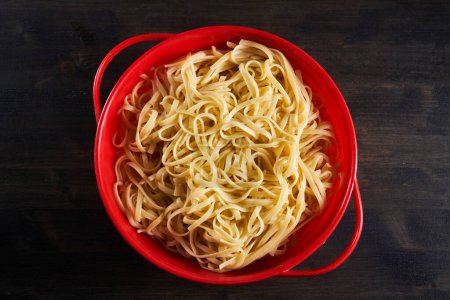 Téléchargez les photos : Boiled noodles in a colander on wooden board - en image libre de droit