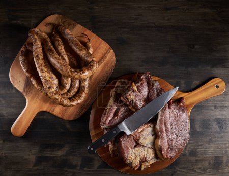 Photo for Smoked pork meat and homemade sausage on a wooden board - Royalty Free Image