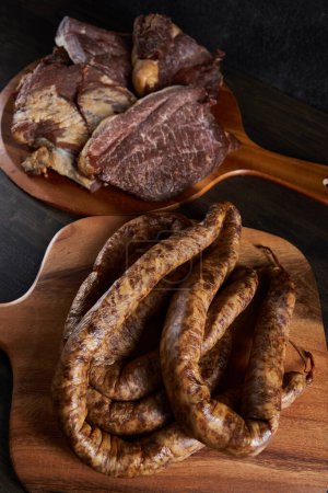 Photo for Smoked pork meat and homemade sausage on a wooden board - Royalty Free Image