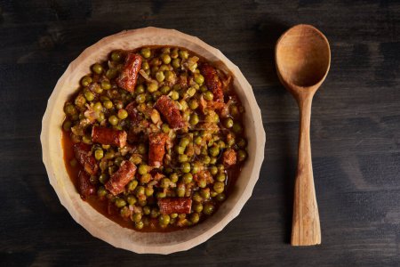 Photo for Pea stew with smoked pork sausages in a wooden bowl - Royalty Free Image