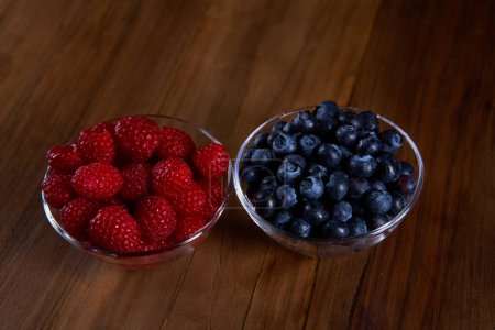 Foto de Raspberries and blueberries in bowls on a wooden board - Imagen libre de derechos
