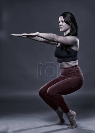 Téléchargez les photos : Monochrome toned of a woman Yoga practitioner in utkatasana, chair, pose - en image libre de droit