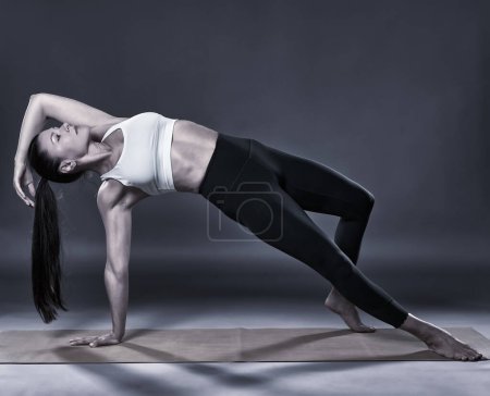 Foto de Monochrome toned of a woman yoga trainer doing Camatkarasana, Wild thing, pose - Imagen libre de derechos