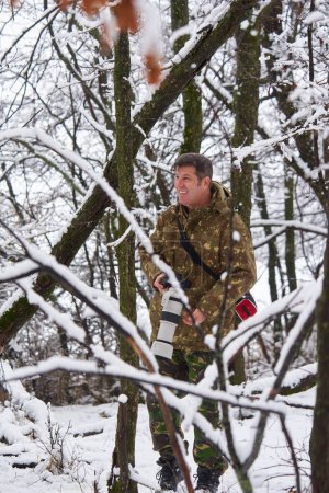 Téléchargez les photos : Professional wildlife photographer in a snowy oak forest with his telephoto lens on camera - en image libre de droit