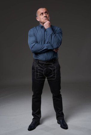 Téléchargez les photos : Full length portrait of a pensive mature businessman on gray background - en image libre de droit