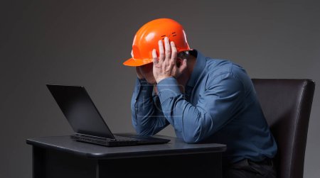 Foto de Ingeniero decepcionado y frustrado en hardhat y traje de negocios comprobar el progreso ineficiente en su computadora portátil - Imagen libre de derechos