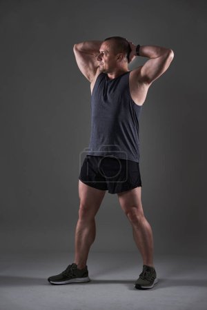 Téléchargez les photos : Plan complet du corps d'un homme mature faisant un entraînement de remise en forme sur fond gris - en image libre de droit
