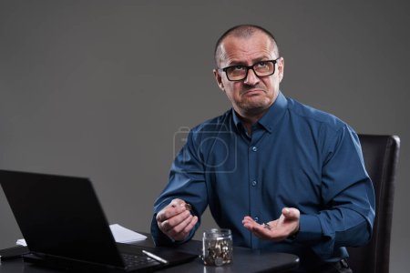 Foto de Hombre de negocios maduro en su escritorio contando centavos, al borde de la bancarrota - Imagen libre de derechos