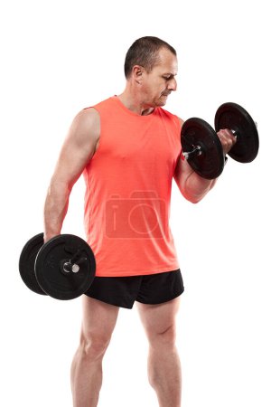 Photo for Mature athletic man in pink tee doing fitness workout with dumbbells, isolated on white background - Royalty Free Image