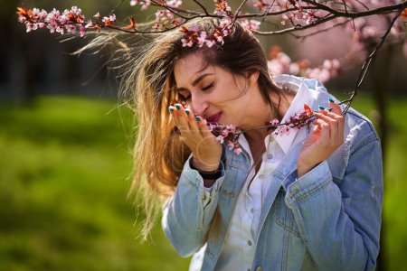 Photo for East asian young woman enjoying spring in a park with flowering trees - Royalty Free Image