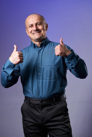 Photo for Happy businessman showing thumbs up sign, over purple background - Royalty Free Image