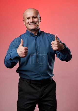 Foto de Amistoso hombre de negocios sonriente haciendo pulgares hacia arriba signo, sobre fondo de color romano - Imagen libre de derechos
