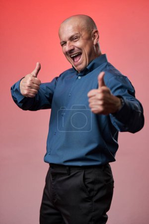 Photo for Friendly smiling businessman making thumbs up sign, over roman color background - Royalty Free Image