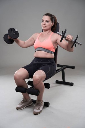 Photo for Strong confident plus size young woman working out fitness exercises with dumbbells - Royalty Free Image