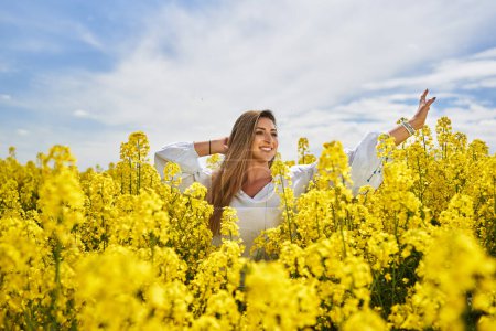 Foto de Retrato de una hermosa mujer hispana rubia en un campo de canola floreciente - Imagen libre de derechos