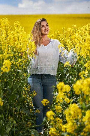 Photo for Portrait of a beautiful blonde hispanic woman in a blooming canola field - Royalty Free Image