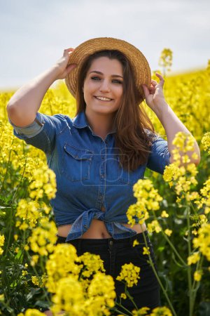 Téléchargez les photos : Portrait rapproché d'une belle femme blonde caucasienne aux yeux bleus dans un champ de canola en pleine floraison - en image libre de droit