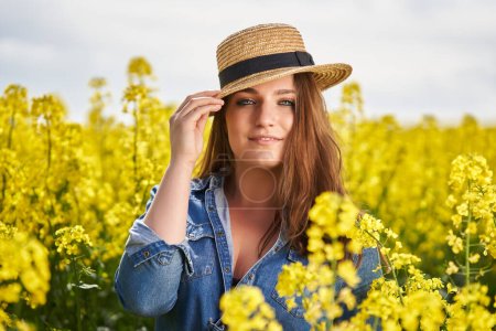 Closeup portrait of a beautiful caucasian blonde woman with blue eyes in a canola field in full bloom