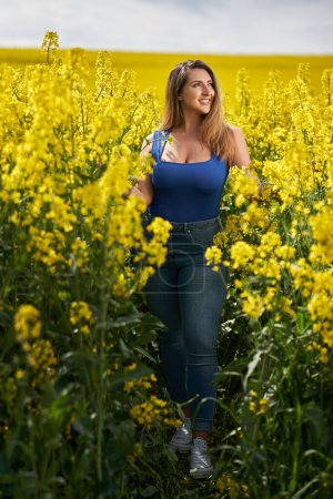 Téléchargez les photos : Belle femme hispanique blonde sensuelle dans un champ de canola en fleurs, portrait glamour - en image libre de droit