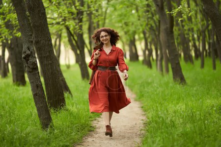 Photo for Candid portrait of a beautiful mature curly hair woman in the park - Royalty Free Image