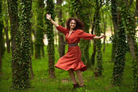 Foto de Retrato cándido de una hermosa mujer de pelo rizado madura bailando feliz en el parque - Imagen libre de derechos