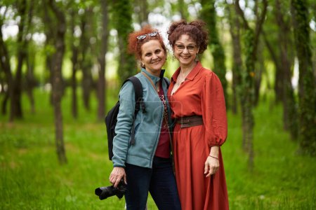 Téléchargez les photos : Femme photographe avec appareil photo et son modèle féminin mature dans le parc - en image libre de droit