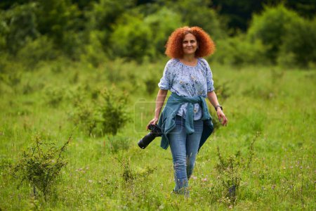 Photo for Woman nature photographer with camera on a meadow in the wilderness - Royalty Free Image